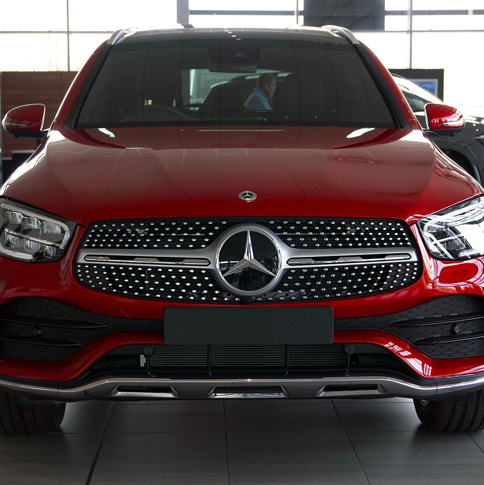 Un Mercedes GLC rouge, de face, dans la salle d'exposition d'une concession.